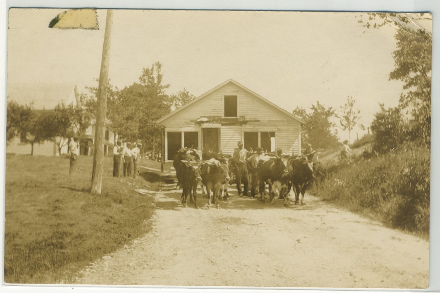 Harry Dority’s shop (or cottage) was being moved from a site on Dority property behind Bob and Jane Sargent’s home to a new location next to the Sargentville Library.  They are coming down the hill and into the center of Sargentville.  The Webb home is to the left.